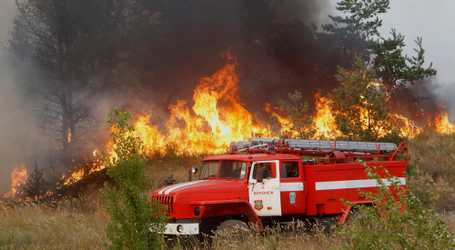 Image: A fire truck parks near burning grass and trees, outside the town of Novovoronezh
